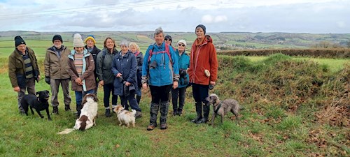 The walking group as they take a break after an uphill climb across the fields to view Morebath in the distance